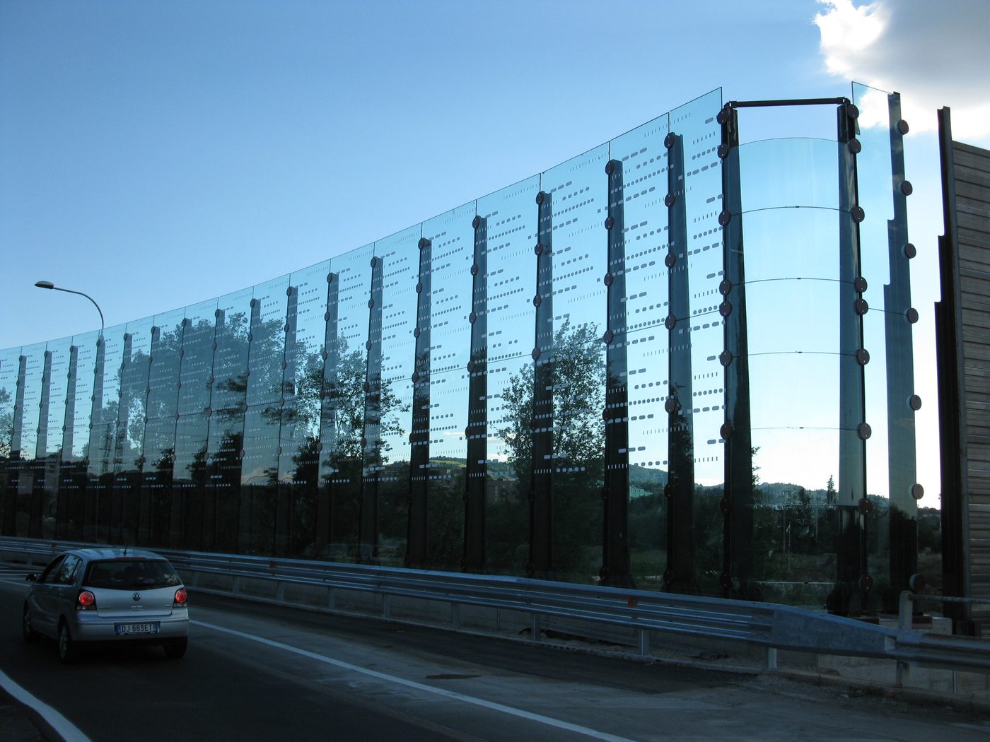 Barriera acustica autostradale in vetro e corten a Bologna, vista laterale con veicoli in transito