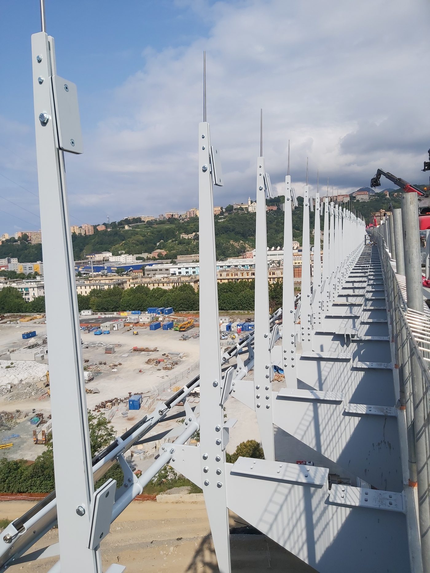 Struttura in acciaio di supporto del parapetto sul Ponte San Giorgio a Genova durante il montaggio, con la città sullo sfondo