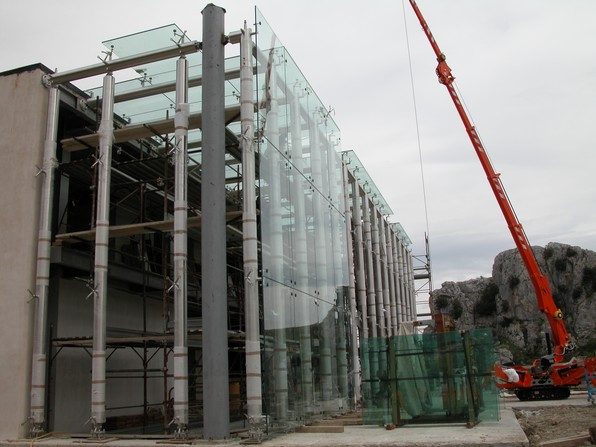 Facciata a ragno in vetro del nuovo museo di Pietrabbondante durante il montaggio, con gru di cantiere