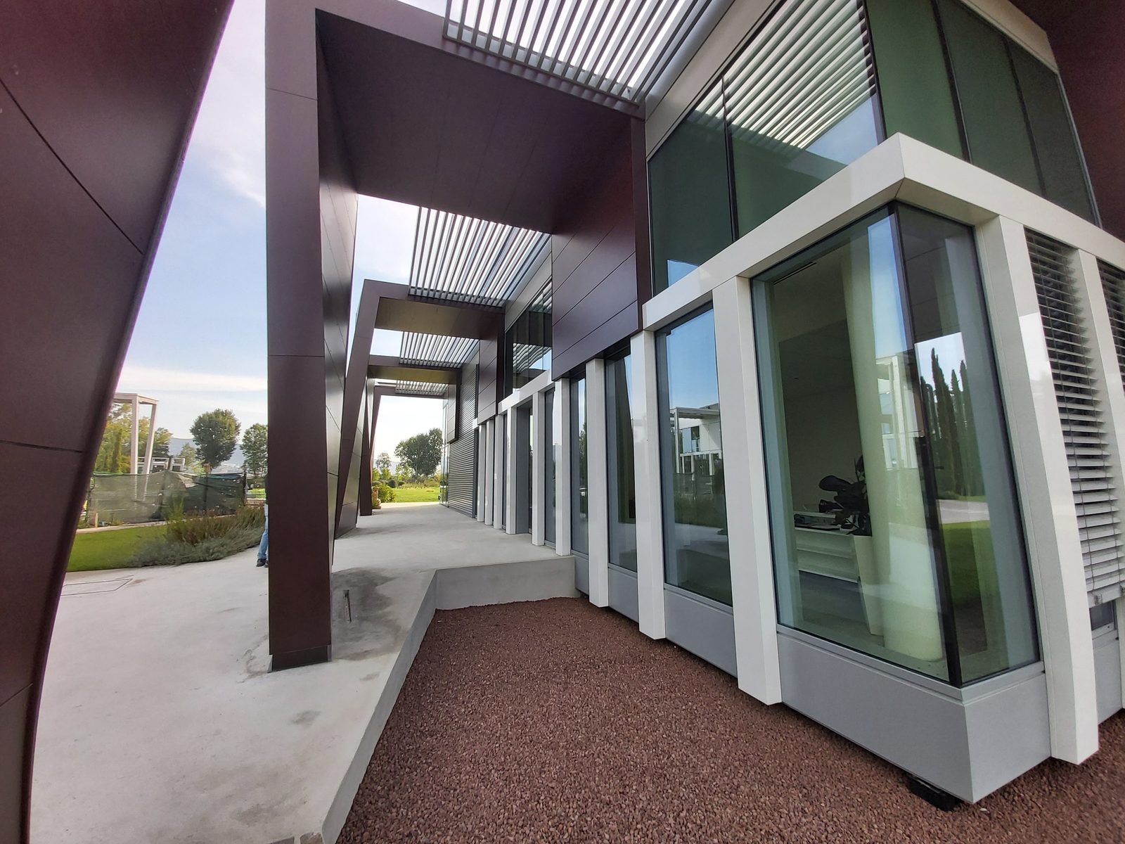 Dettaglio della facciata continua vetrata con montanti bianchi e pergola frangisole in alluminio, sede Sterling S.p.A.