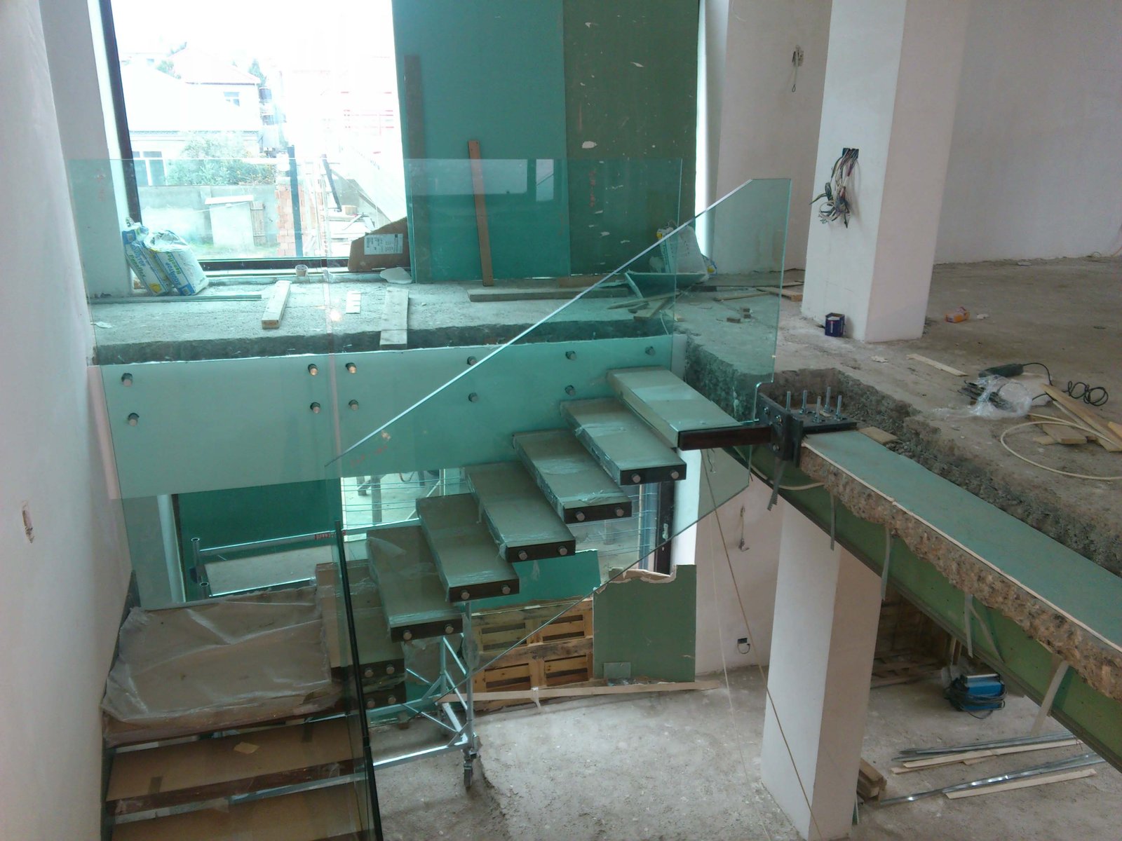 Mensole in acciaio a sbalzo fissate a muro durante il montaggio di una scala interamente vetrata, cantiere a Baku